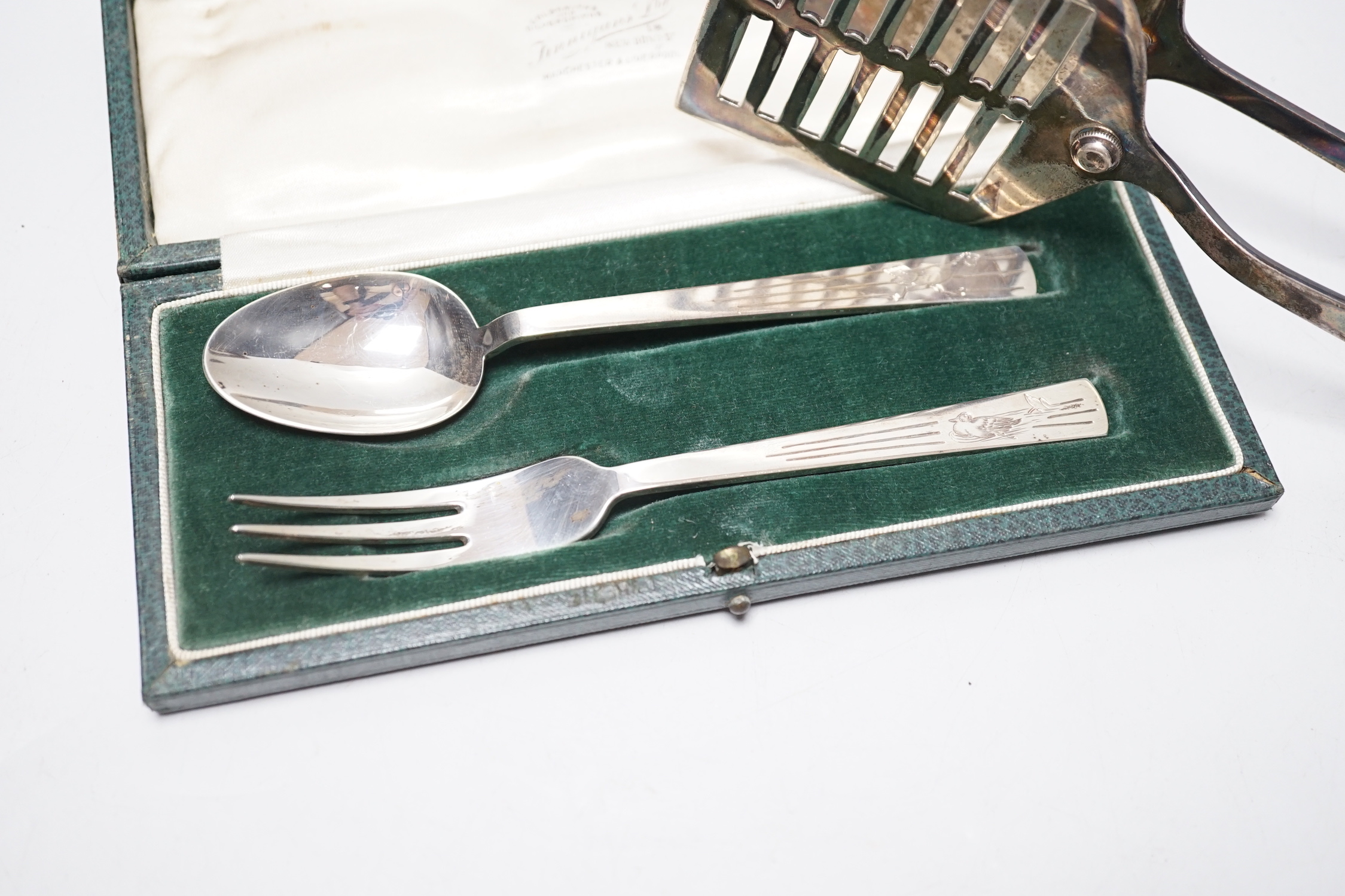 A cased George VI silver christening spoon and fork, by Robert Edgar Stone, London, 1938 and a pair of George V silver asparagus servers.